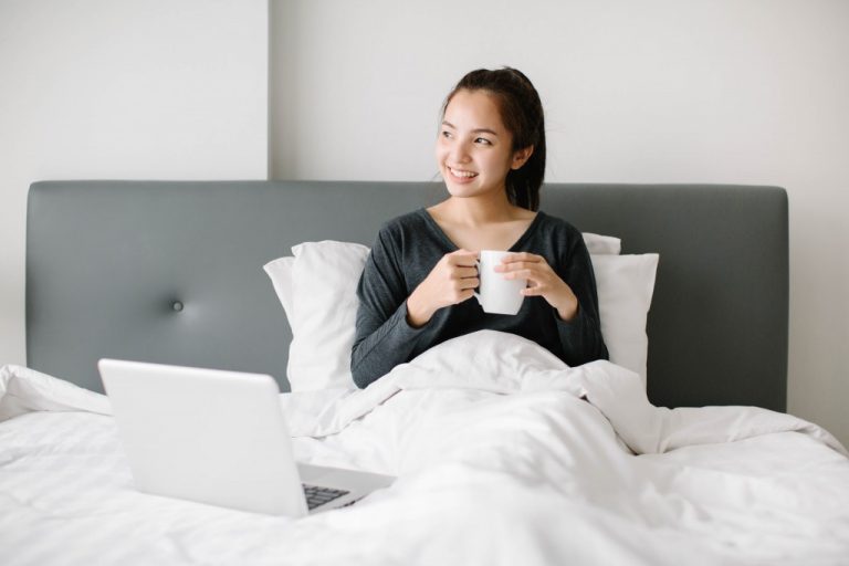 woman holding a cup of coffee in bed